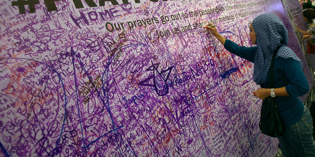 A woman leaves a message for passengers aboard a missing Malaysia Airlines plane, at a shopping mall in Petaling Jaya, near Kuala Lumpur. Photo / AP