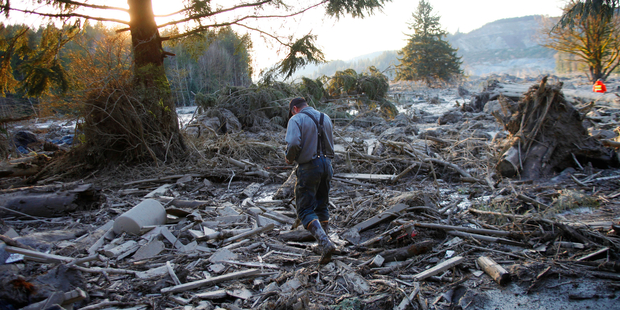 Steve Skaglund walks across the rubble on the east side of Saturday's fatal mudslide near Oso, Washington. Photo / AP