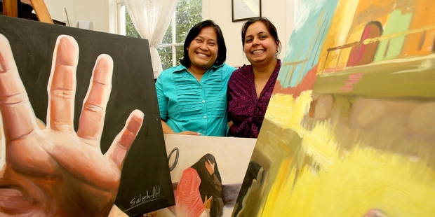 Sonia Pathak and Lisda Anggraeni from Shakti Ethnic Women's Support Group show some of the paintings that will be for sale. PHOTO/RUTH KEBER