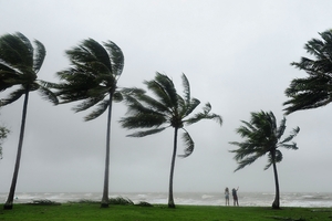 As high winds rip through Port Douglas a Coastguard volunteer, below, prepares for the cyclone. GETTY IMAGES