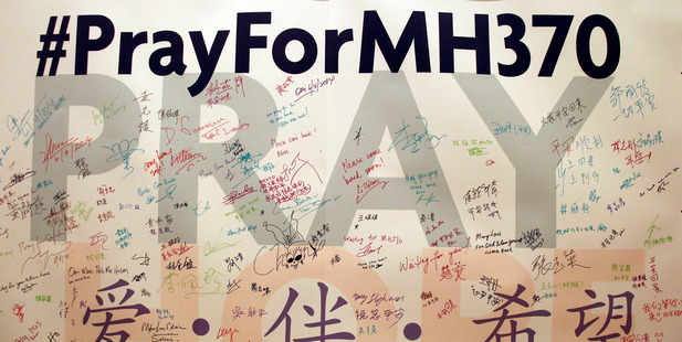 A man writes messages for passengers aboard the missing Flight MH370 before a mass prayer for them, in Kuala Lumpur. Photo / AP