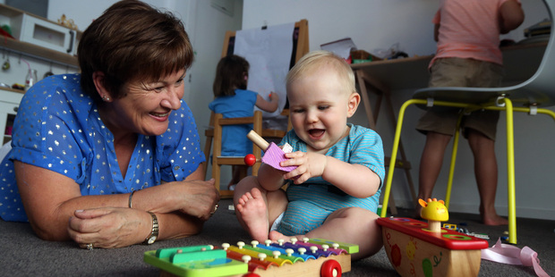 Jody Bradfield plays with Harry Prestidge, 9 months, as Isla Prestidge (back left), 4, and Oscar Prestidge, 6, occupy themselves in their playroom in Meadowbank. Photo / Jason Oxenham