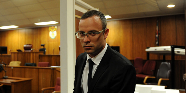 After a postponement was announced, Oscar Pistorius walks past the exhibited door, directly behind him, in court, through which he shot and killed Reeva Steenkamp. Photo / AP
