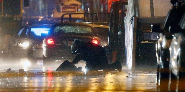 A bomb squad member inspects an object after a detonation at the finish line. Photo / AP