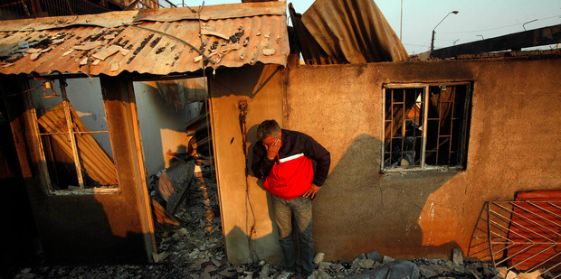 A man cries next to the remains of his house after a forest fire destroyed it in Valparaiso, Chile. Photo / AP