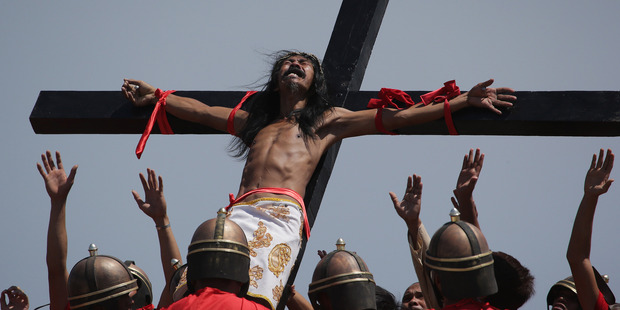 A Filipino devotee that is nailed to a cross reacts as actors dressed as Roman soldiers lift him as they re-enact the crucifixion of Jesus Christ. Photo / AP