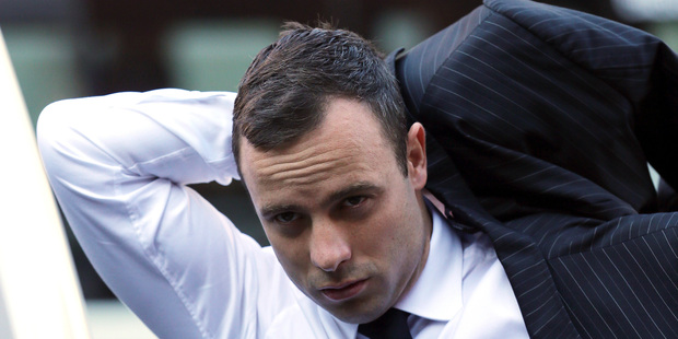 Oscar Pistorius puts on his jacket as he arrives at the high court in Pretoria, South Africa. Photo / AP