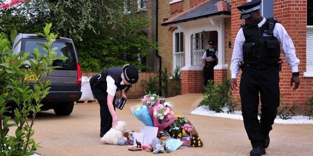 Police officers adjust tributes left outside the house in New Malden, south London. Photo / AFP
