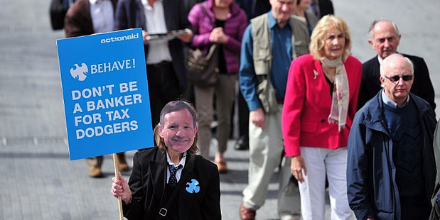 A protester opposing tax evasion by banks wears a mask showing the face of a Barclays executive. Photo / AFP