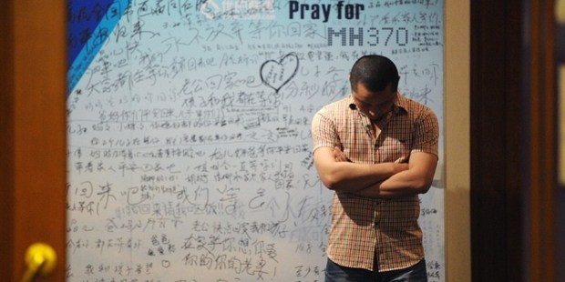 A man stands in front of a billboard as a meeting for Chinese relatives of those lost on MH370 are updated on the search. Photo / AFP