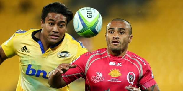 Reds halfback Will Genia looks to control a loose ball under pressure from Hurricane Julian Savea. Photo / Getty Images