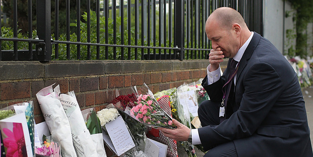 Steve Mort, head teacher of Corpus Christi Catholic College, reads the hundreds of tributes left in honour of slain teacher Ann Maguire. Photo / Getty Images