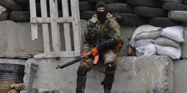 A masked and armed pro-Russian militant guards barricades near Slovyansk. Photo / AP