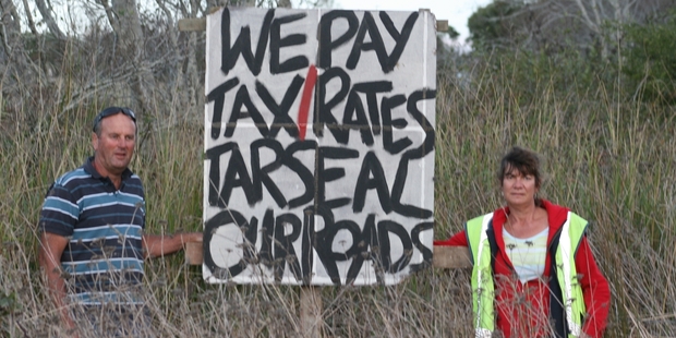 Pipiwai Rd farm owner Mark Croucher and Alex Wright of Pipiwai Titoki Road Action Group with one of the signs the group has put up in the area.
