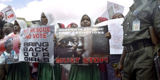 A policeman stand beside children calling for the release of missing Chibok school girls at the state government house, in Lagos, Nigeria. Photo / AFP
