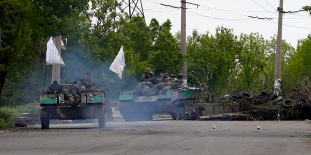 Pro-Russian gunmen atop armored carriers pass by barricades on a road leading into Slovyansk, eastern Ukraine. Photo / AP