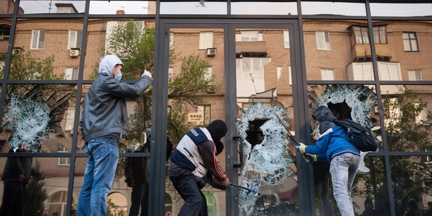 Pro-Russian activists break the glass of the offices of Industrial Union of Donbass Corporation in Donetsk. Photo / AP