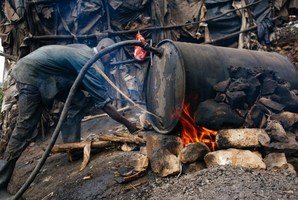 A man stoking the fire of a distillery that makes potentially fatal homebrew.
Photo / AFP