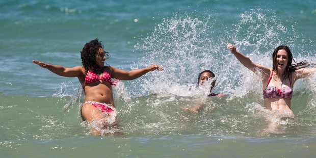 Cailin Brown (left), Monique Adams and Amy Coleman enjoy a refreshing dip at Long Bay, Auckland, yesterday. Photo / Greg Bowker