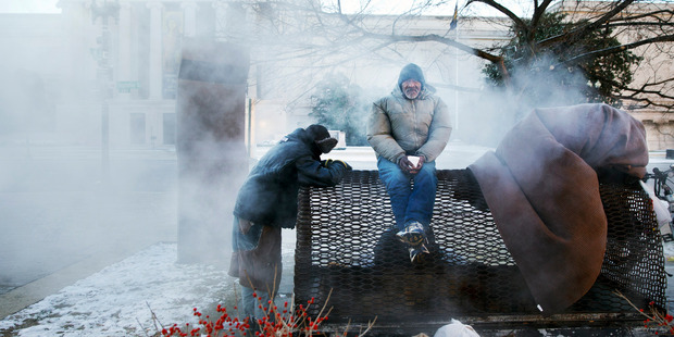 Four homeless men warm themselves on a steam grate by the Federal Trade Commission, blocks from the Capitol, during frigid temperatures in Washington. Photo / AP