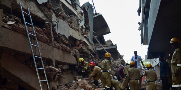 Rescue workers stand amid the debris of a building that collapsed in Canacona. Photo / AP