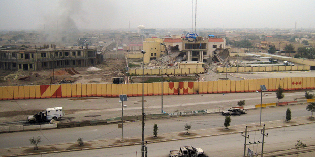 An empty street shows burned vehicles as buildings including a provincial government building, center in the background, are seen damaged in Fallujah, Iraq. Photo / AP