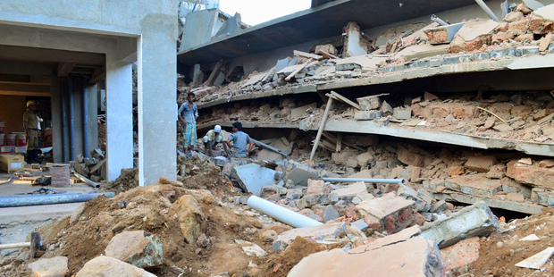 Indian workers stand amid the debris of a building that collapsed in Canacona. Photo / AP