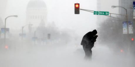 A person struggles to cross a street in blowing and falling snow in St. Louis. Photo / AP