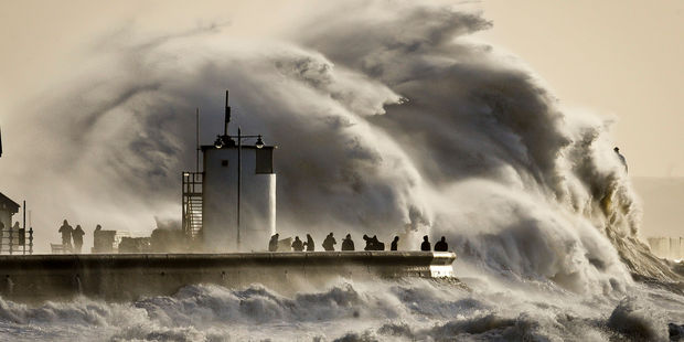 People watch and photograph enormous waves as they break, on Porthcawl harbour, South Wales. Photo / AP
