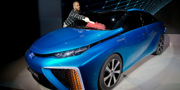 A production crew member dusts off Toyota's FCV hydrogen electric concept car during the International Consumer Electronics Show. Photo / AP