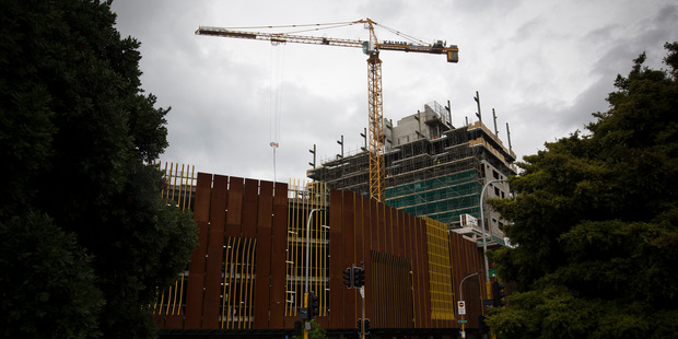 A crane moves construction materials onto the 10-storey apartment tower in the Merchant Quarter, on McCrae Way, New Lynn. Photo / APN