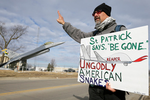 A man waves to a passing car during an anti-drones protest at the Iowa Air National Guard base. Photo/ AP