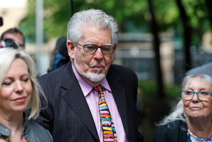 Veteran Australian entertainer Rolf Harris, centre, who is accused of indecent assault, accompanied by members of his family as he arrives at court. Photo / AP
