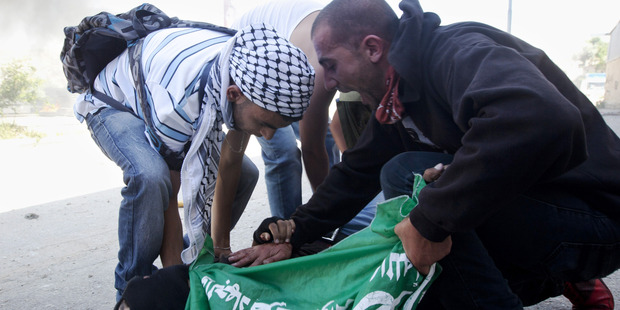Men rush to the aid of Palestinian Mohammad Abu Daher, 17, moments after he is killed in a clash with Israeli troops near the West Bank city of Ramallah. Photo / AP