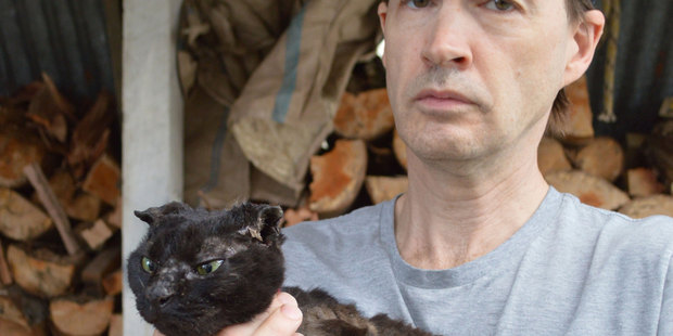 John Bennett, with his sister's cat Midnight, which someone stole and set alight. Photo / Greymouth Star