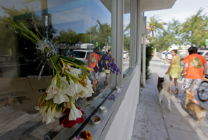 Flowers are placed through a bullet hole on a window of IV Deli Mart, where part of Friday night's mass shooting took place. Photo / AP