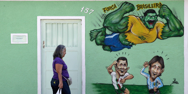 A mural depicting Brazilian soccer player Hulk flying over Argentina's Lionel Messi, and Portugal's Cristiano Ronaldo in Rio. Goldman Sachs tips Brazil to win the World Cup. Photo / AP