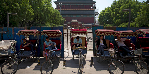Chinese trishaw drivers wait for customers at a compound being fenced up for refurnishing near the drum tower. Photo / AP