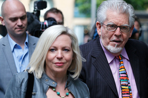 Veteran Australian entertainer Rolf Harris, centre, who is accused of indecent assault, holds his daughter Bindi's hand as he walks into court. Photo / AP
