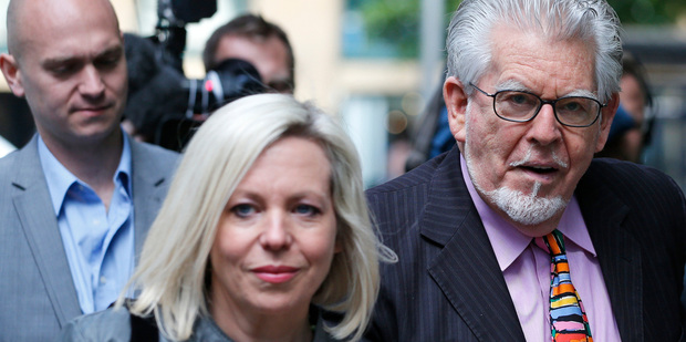 Veteran Australian entertainer Rolf Harris, centre, who is accused of indecent assault, holds his daughter Bindi's hand as he walks into court. Photo / AP