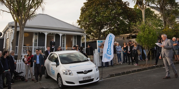 Crowds gather outside the Ponsonby villa as auctioneer Mark Sumich gets under way. Photo / Greg Bowker