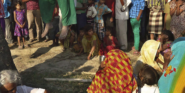 Villagers look at the bodies of the two sisters swaying in the breeze as they wait for police to make arrests. Photo / AP