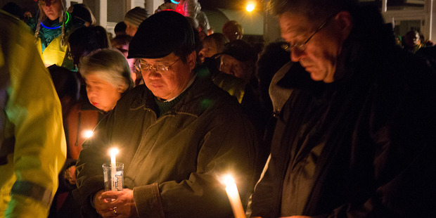Antonio Gotingco, left, husband of murdered woman Blessie Gotingco , prays with a large group of locals who have gathered to honour her memory. Photo / Herald on Sunday / Steven McNicholl