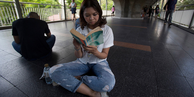 Kasama Na Nagara, who works in the financial sector, reads a book along an elevated walkway during a protest in Bangkok, Thailand. Photo / AP