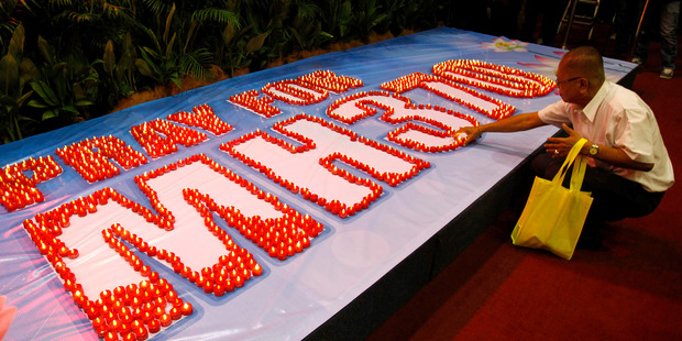 A man places a LED candle at a mass prayer for passengers onboard Flight MH370. Photo / AP