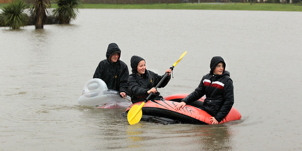 Hamish McEwan, 15, Rose McEwan, 16, and James McEwan, 12 paddle their inflatable lilos on a flooded play ground in Rangiora. Photo / Getty Images