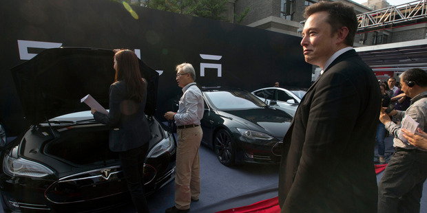 Tesla Motors CEO Elon Musk, right, looks on as a set of Tesla Model S sedans are delivered to its first Chinese customers at an event in Beijing earlier this year. Musk announced today that many of the Telsa patents will be open to rivals. Photo / AP