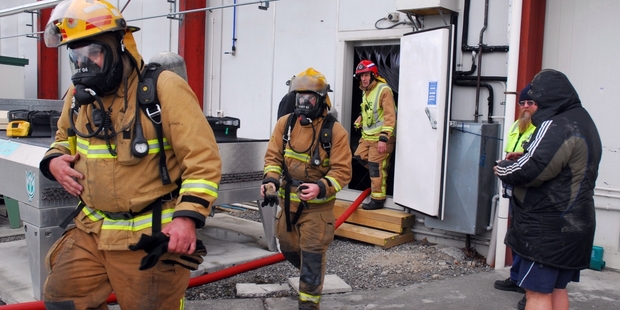 JOB DONE: Firefighters in breathing apparatus are flanked by bakery workers as they emerge from the smoke-filled depths of Breadcraft, a multi-million-dollar artisan bread plant in Pragnell St, Masterton.PHOTO/NATHAN CROMBIE