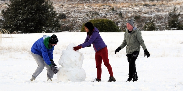 Tourists enjoy the snow on the lawn of the Chateau Tongariro at National Park. Photo / SNPA
