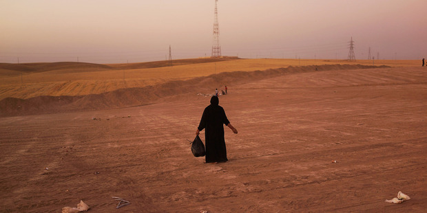 An Iraqi woman walks in a field beside a temporary displacement camp for Iraqis caught-up in the fighting in and around the city of Mosul in Kalak, Iraq. Photo / Getty Images